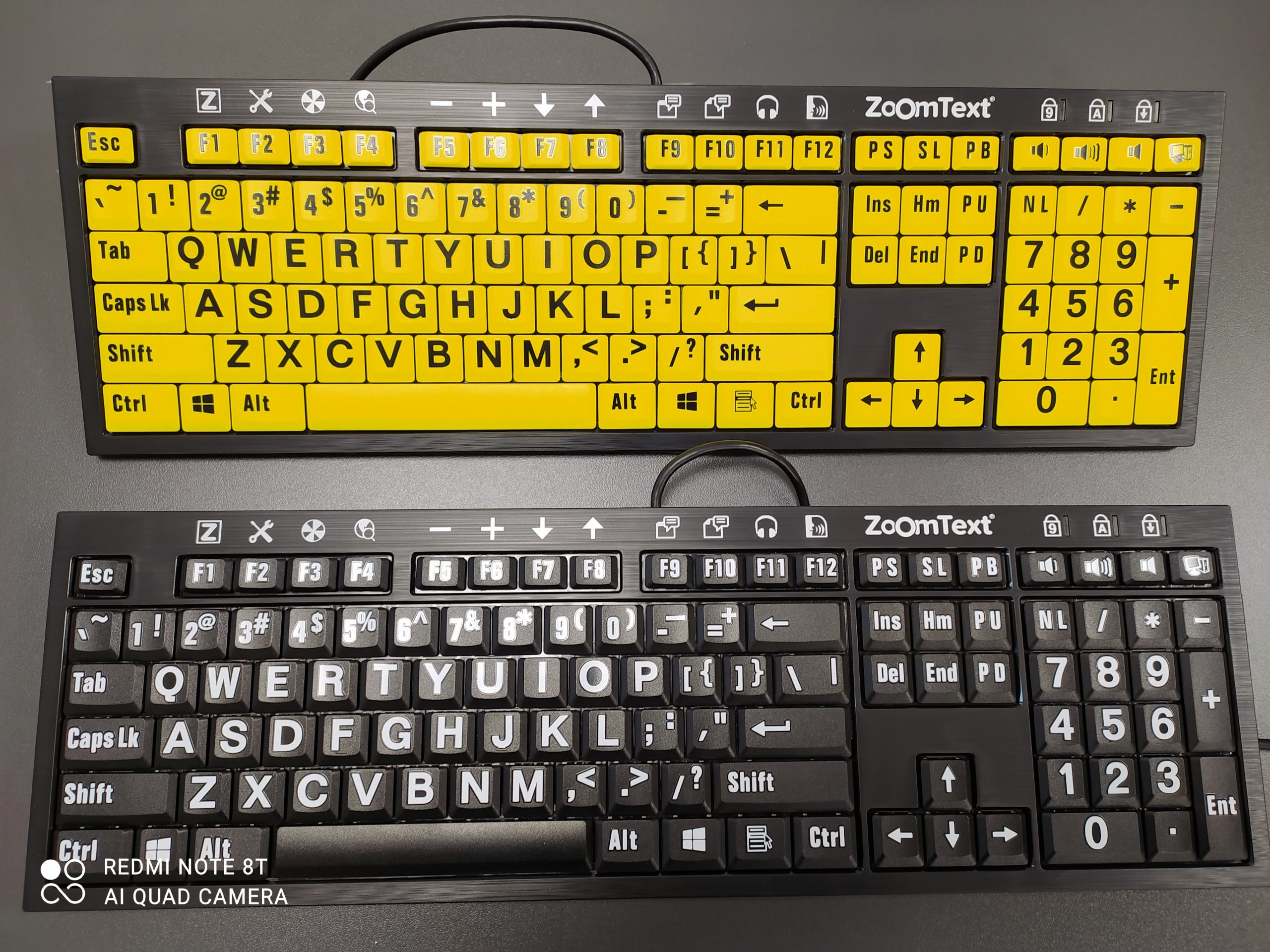 Dwie klawiatury ZoomText w wersji z żółtymi klawiszami i czarnymi literami, oraz czarne klawisze i białe litery.
